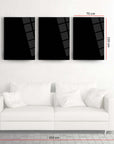 Set of three black glass wall art pieces above a white couch, dimensions displayed in metric.