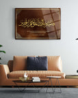 Yusuf Suresi 64. Ayet 2 gold calligraphy glass art on a modern living room wall.