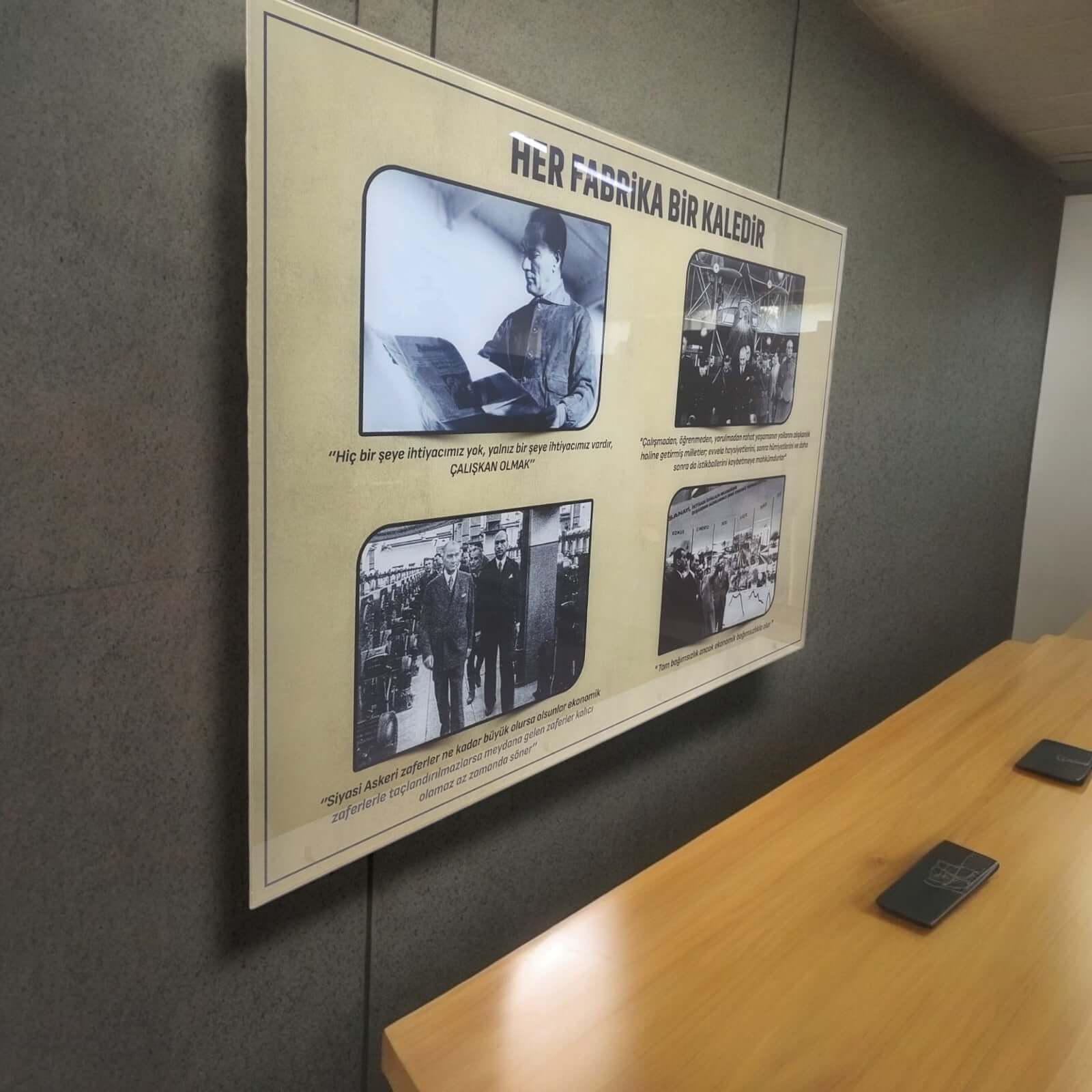 Framed display with historical factory photographs and quotes on a wall.