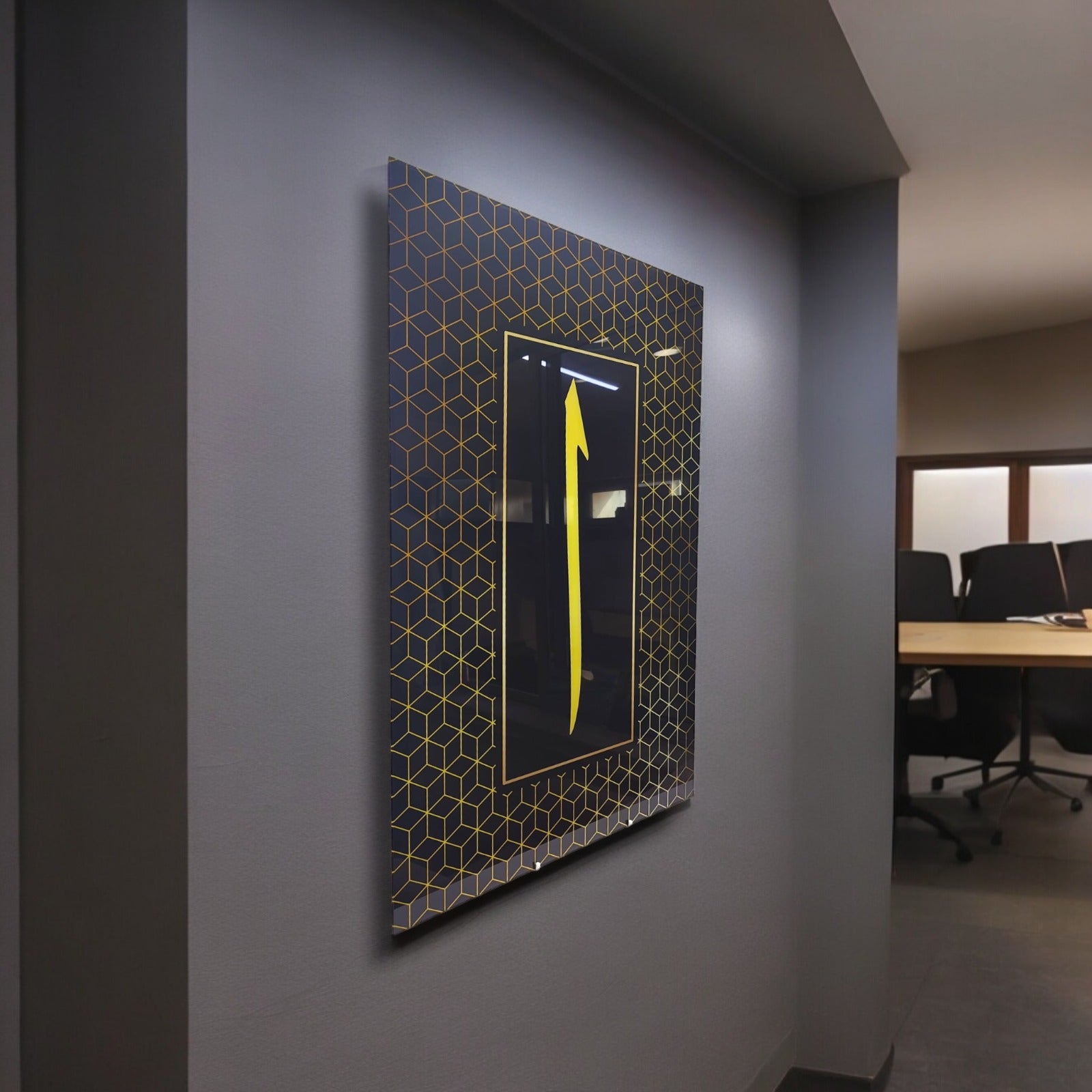 Decorative wall art with a yellow arrow on a patterned black background in a modern office setting.