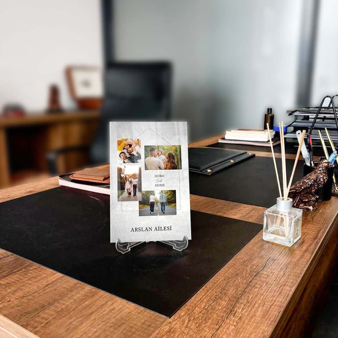 Kişiye özel tasarım cam tablo, modern ofis masasında sergileniyor, aile fotoğraflarıyla kişiselleştirilmiş.