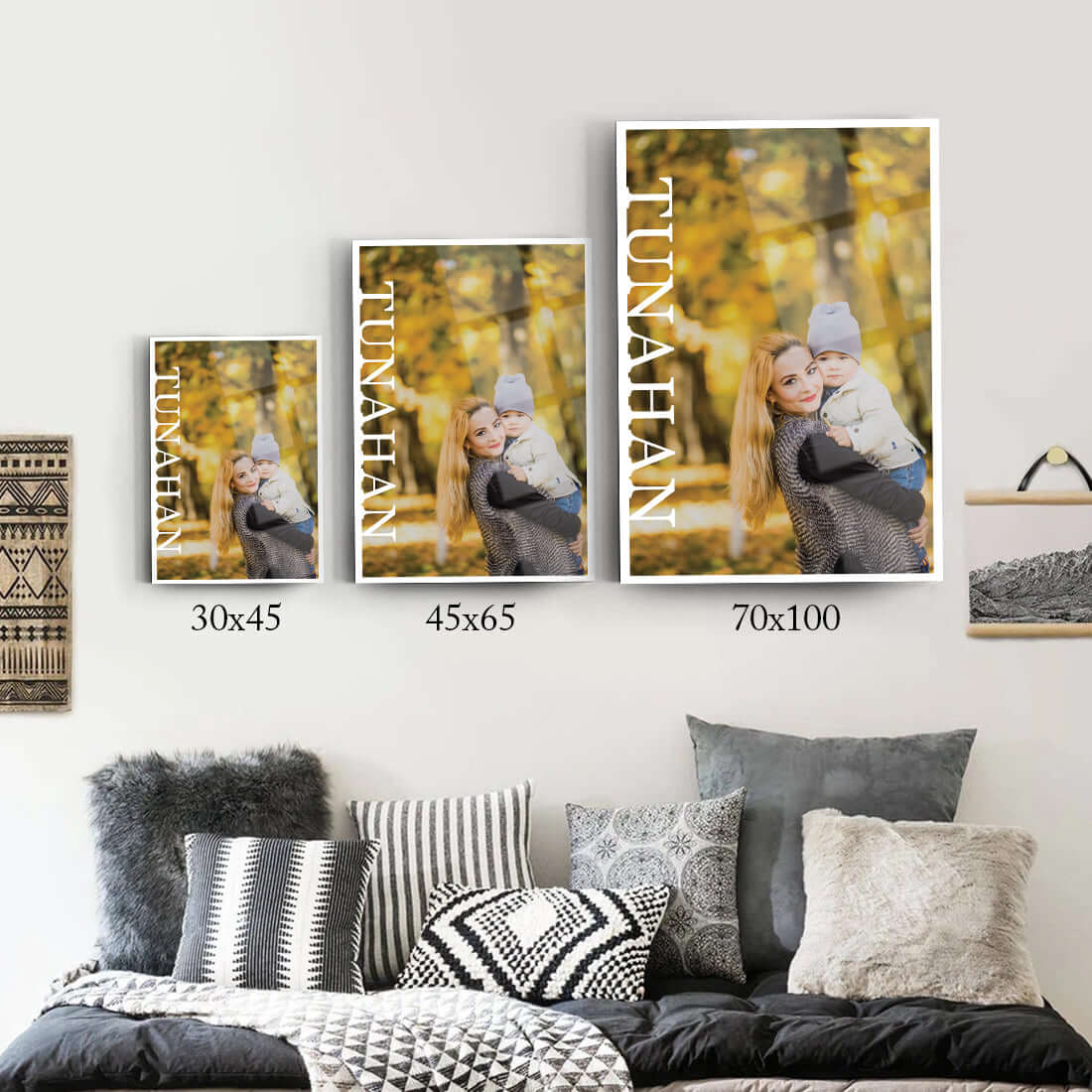 Three framed pictures of a woman holding a child, displayed in varying sizes on a modern wall.