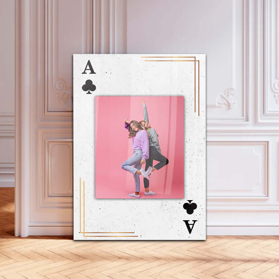 A stylish framed photo depicting two playful girls posing in front of a pink background with an Ace of Spades design.
