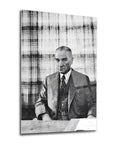 Black and white portrait of a man in a suit sitting at a table, with a checkered background.