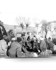 Historical gathering of men in traditional attire, discussing in a rural setting.