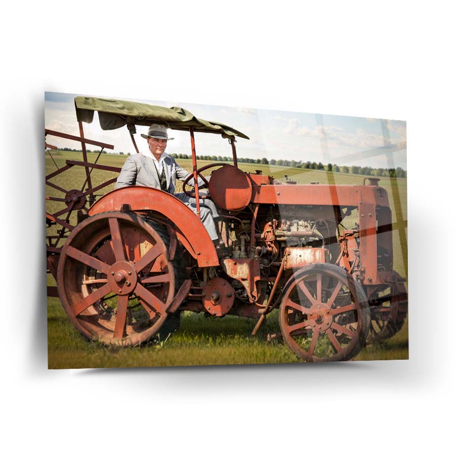 Vintage man with hat on old red tractor in a field, showcasing agricultural heritage and nostalgia.
