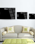 Modern wall art sizes shown in black rectangular glass designs above a stylish sofa with green cushions.