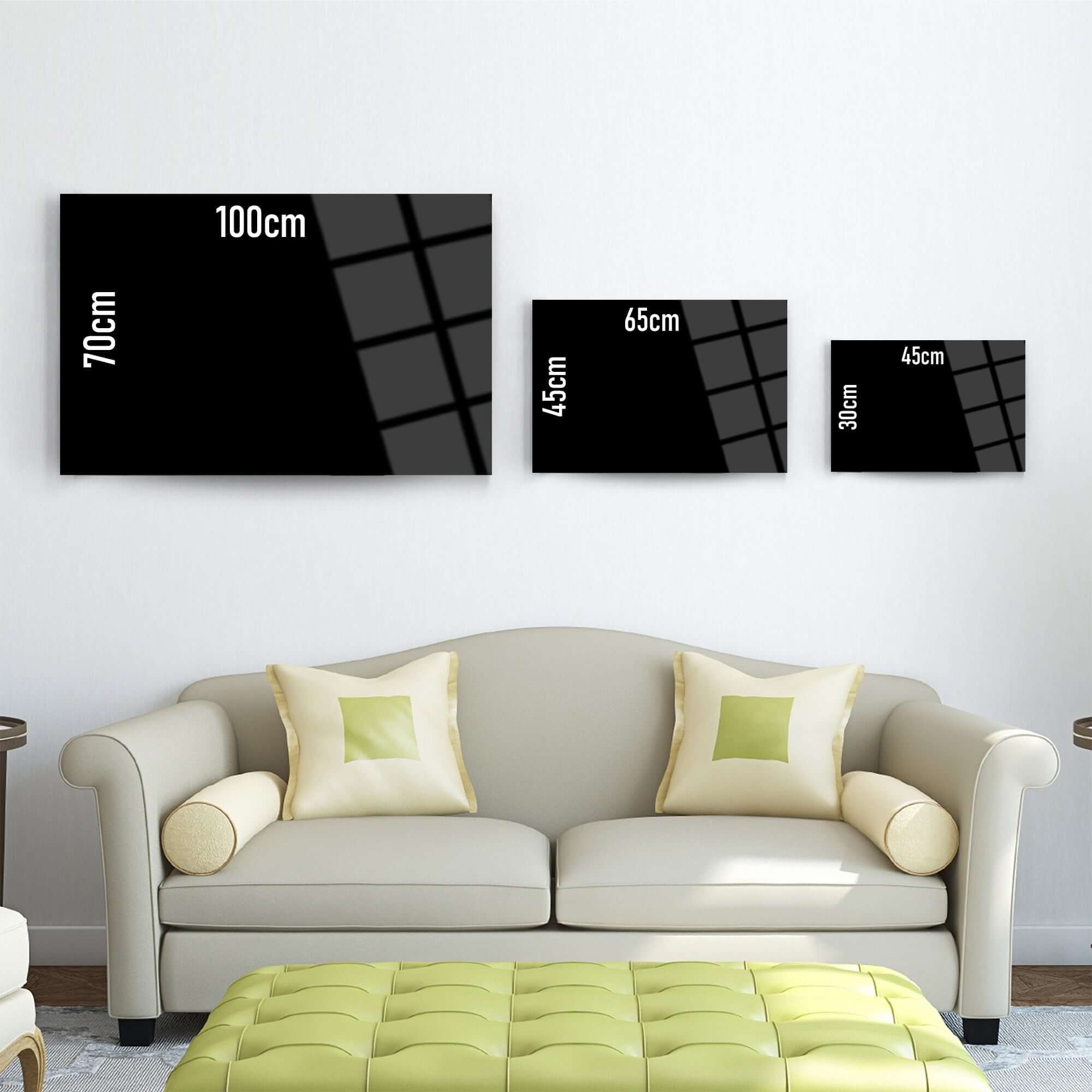Stylish black wall art in three sizes displayed above a modern sofa with green cushions.