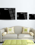 Modern wall art display with three sizes of black cam tablolar above a stylish cream couch.