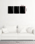 Modern 3-piece black glass wall art above a stylish white sofa, showcasing dimensions for perfect placement.