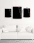 Decorative black glass art set on a wall above a modern white sofa, showcasing measurements for stylish home decor.