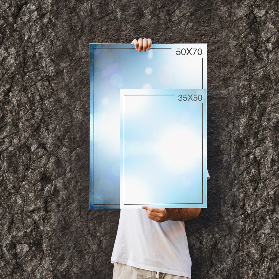 Person holding two sizes of glass frames, one 50x70cm and one 35x50cm, against a textured background.