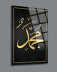 Elegant glass wall art depicting the name Muhammad in golden calligraphy on a black background.