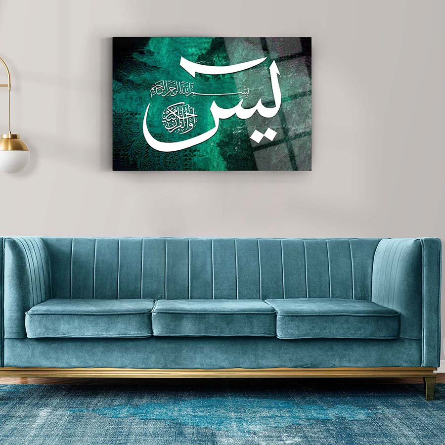 Yasin Cam Tablo showcased above a modern blue sofa, featuring intricate calligraphy art on glass.