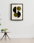 Modern art print featuring abstract circular shapes in earthy tones, displayed on a minimalistic wall with greenery.