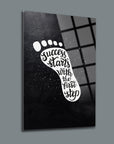 Artistic glass wall decor featuring the quote 'Success starts with the first step' in a foot design.