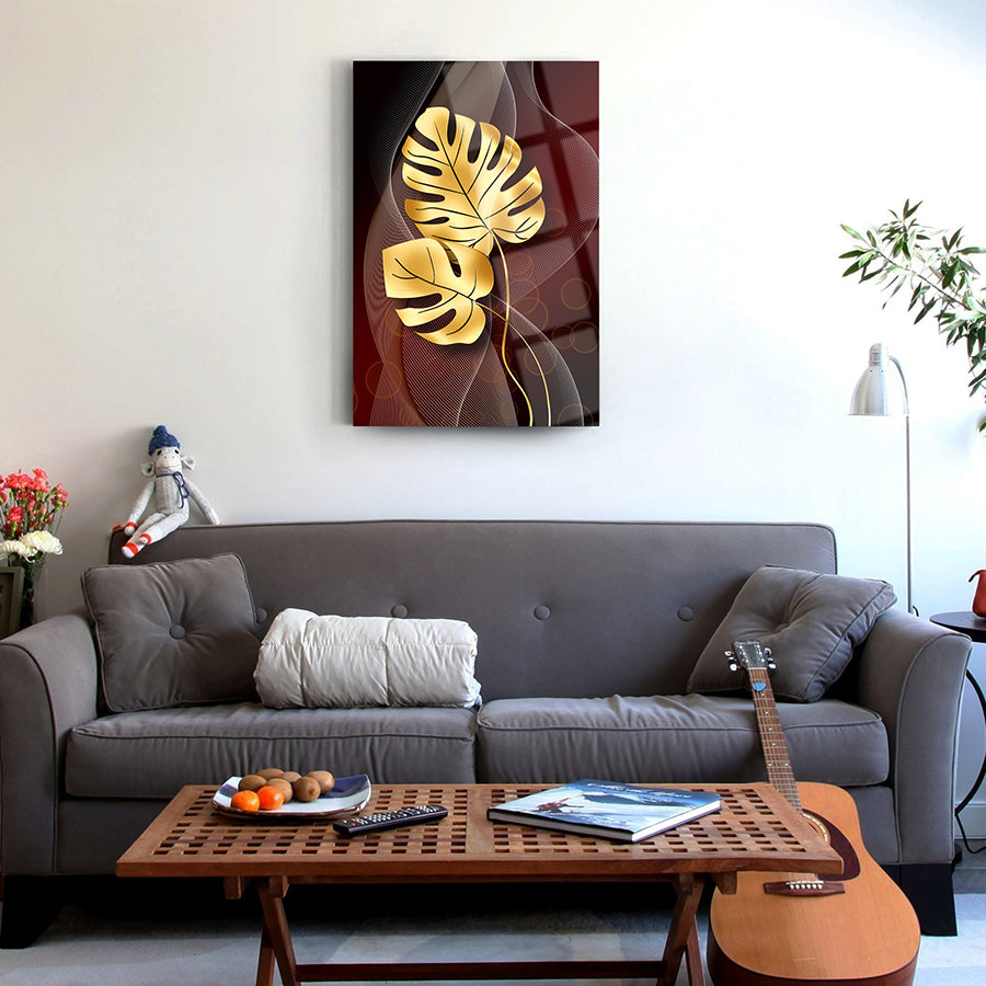 Elegant gold palm leaf glass artwork on a living room wall above a cozy grey sofa and coffee table.