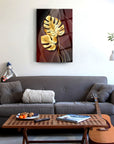 Elegant gold palm leaf glass artwork on a living room wall above a cozy grey sofa and coffee table.