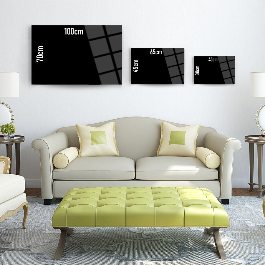Modern living room with three black glass artworks in various sizes above a stylish sofa.