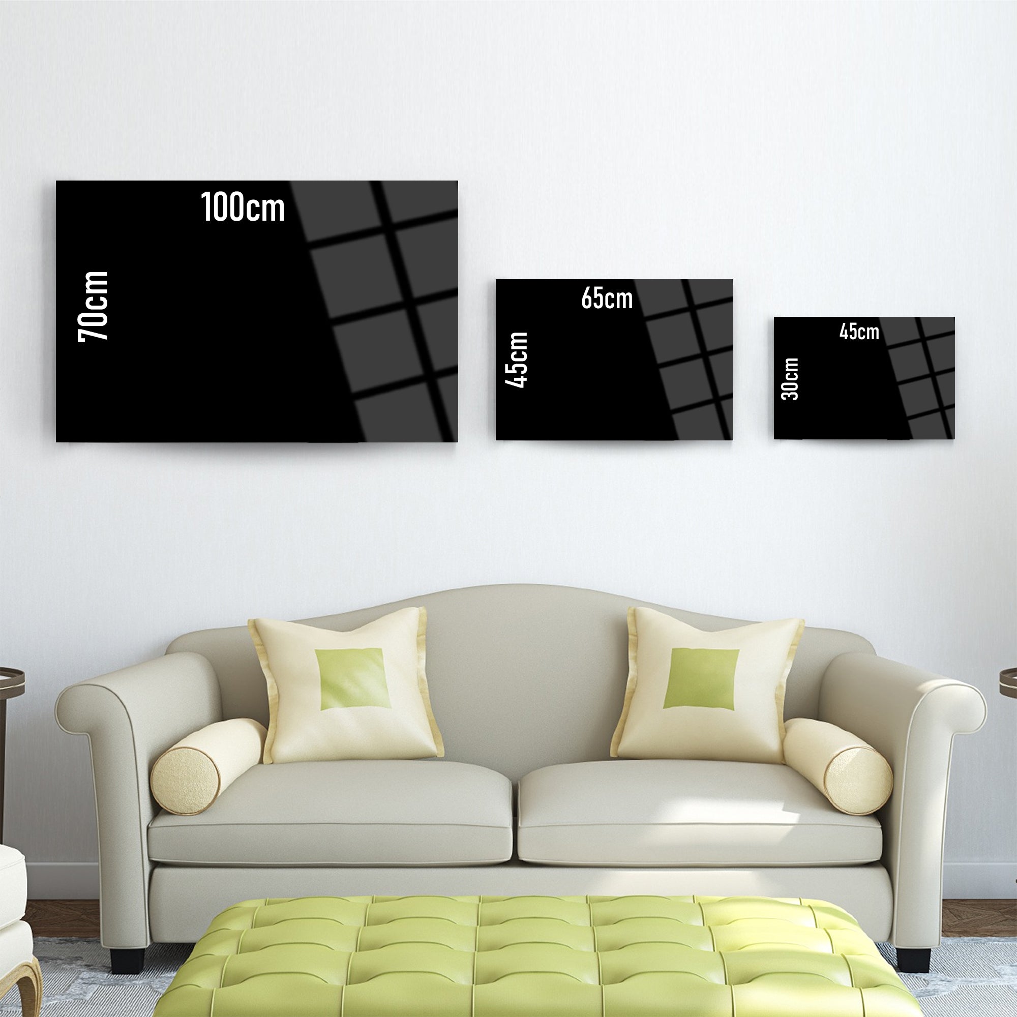Three different sizes of glass wall art displayed above a light sofa, showcasing dimensions on each piece.