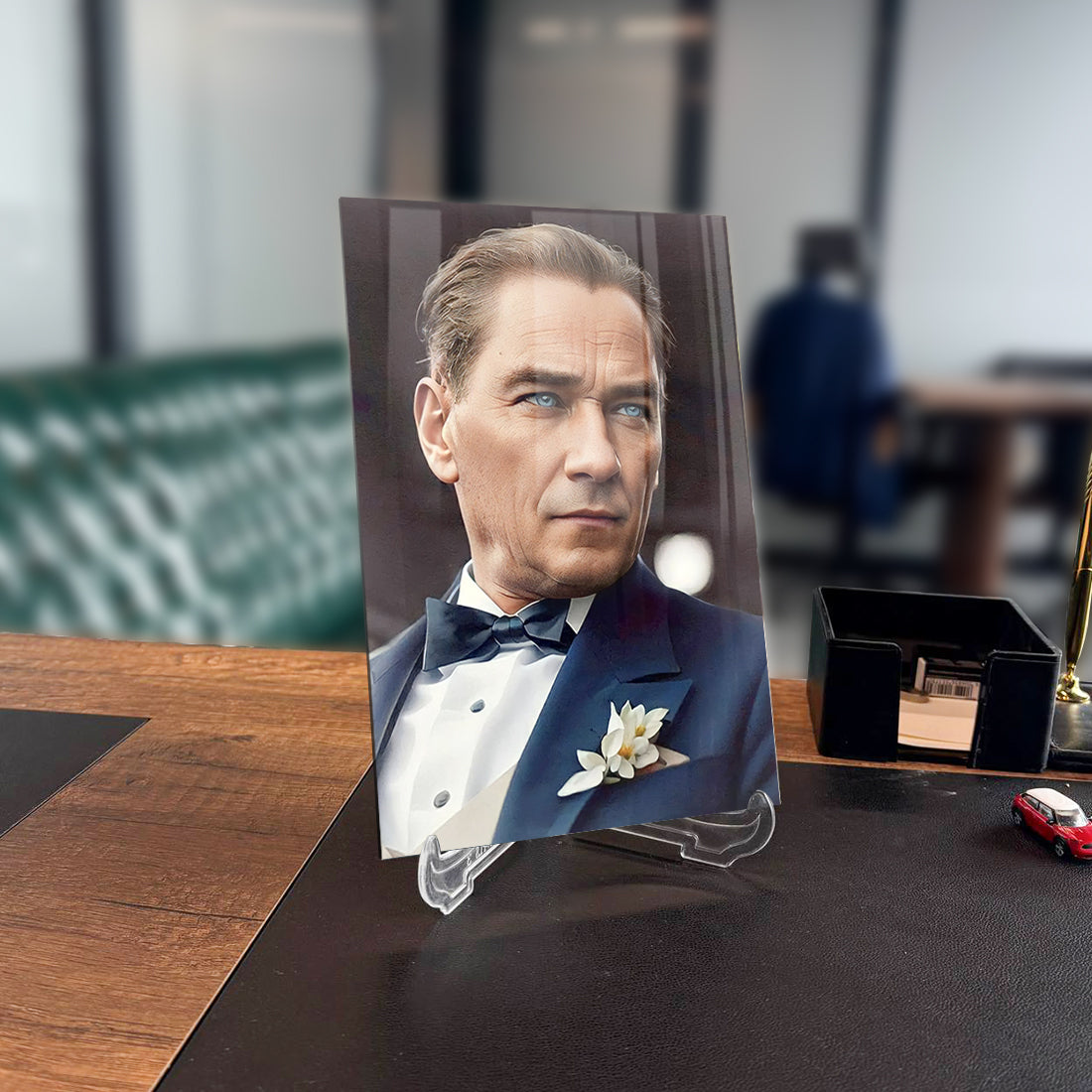 Elegant man in a tuxedo displayed on a glass stand in a stylish office setting.