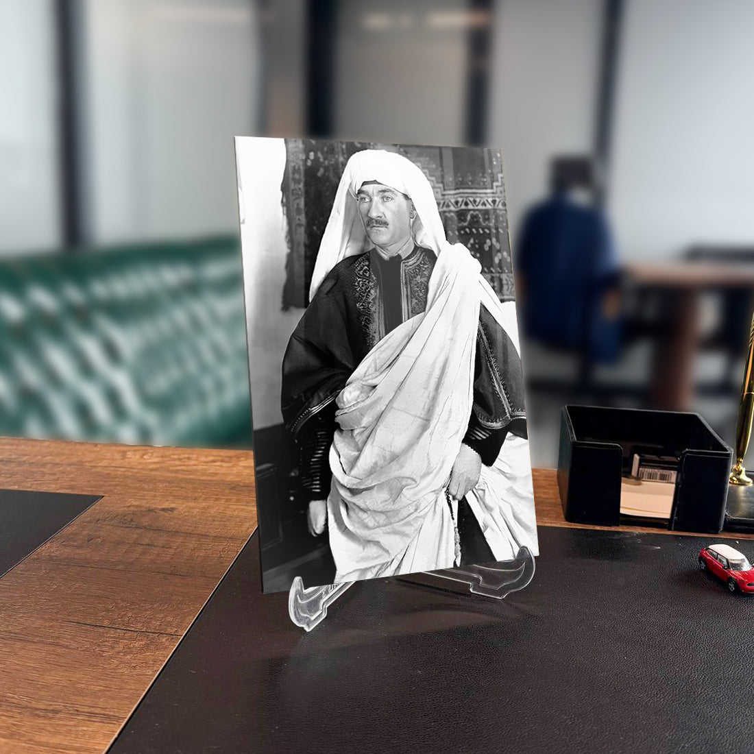 Black and white photo of a man dressed in traditional attire, displayed on a modern desk with an elegant background.